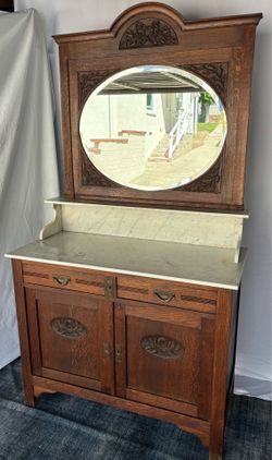 Antique oak washstand / bathroom vanity with a marble top, oval beveled mirror, and floral carvings