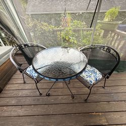 Glass top wrought iron table and 2 matching chairs with cushions