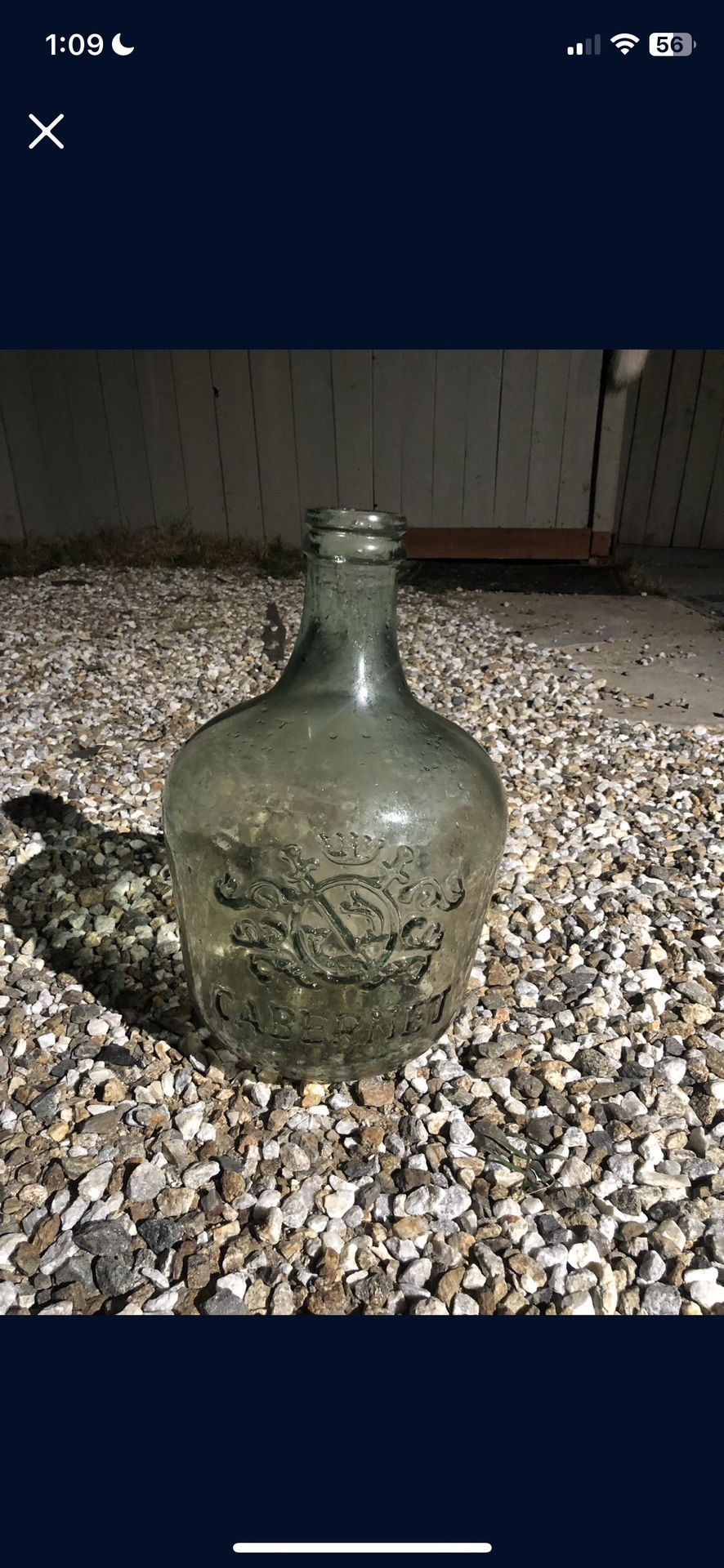 antique green glass demijohn or wine jug with an embossed crest