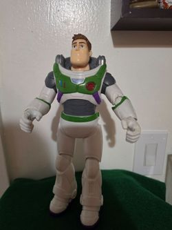 Large Disney Pixar Buzz Lightyear action figure is 12 inches tall. This plastic toy has a white, green, and grey space suit with purple accents. It is