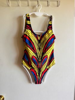 Eye-catching yellow one-piece with bold red and blue accents. Comfortable stretch fabric for active play and swim. Scoop neckline and full coverage de