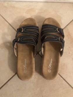 A pair of brown-and-black women’s slide sandals with two adjustable-looking straps and decorative stitching. Brand “Forever.” New