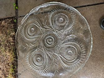 This clear pressed glass platter features intricate geometric patterns.