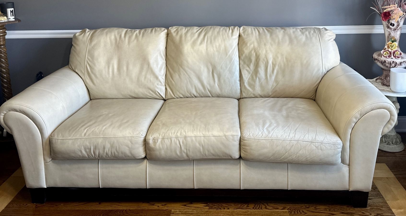 Leather Sofa-Ashley Furniture-Cream Color. 3 Seat with Cherry Color Wood Trim- Used in good condition.