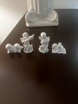 Elegant set of white resin cherub figurines. This collection includes multiple small angels in various poses, including some playing musical instrumen