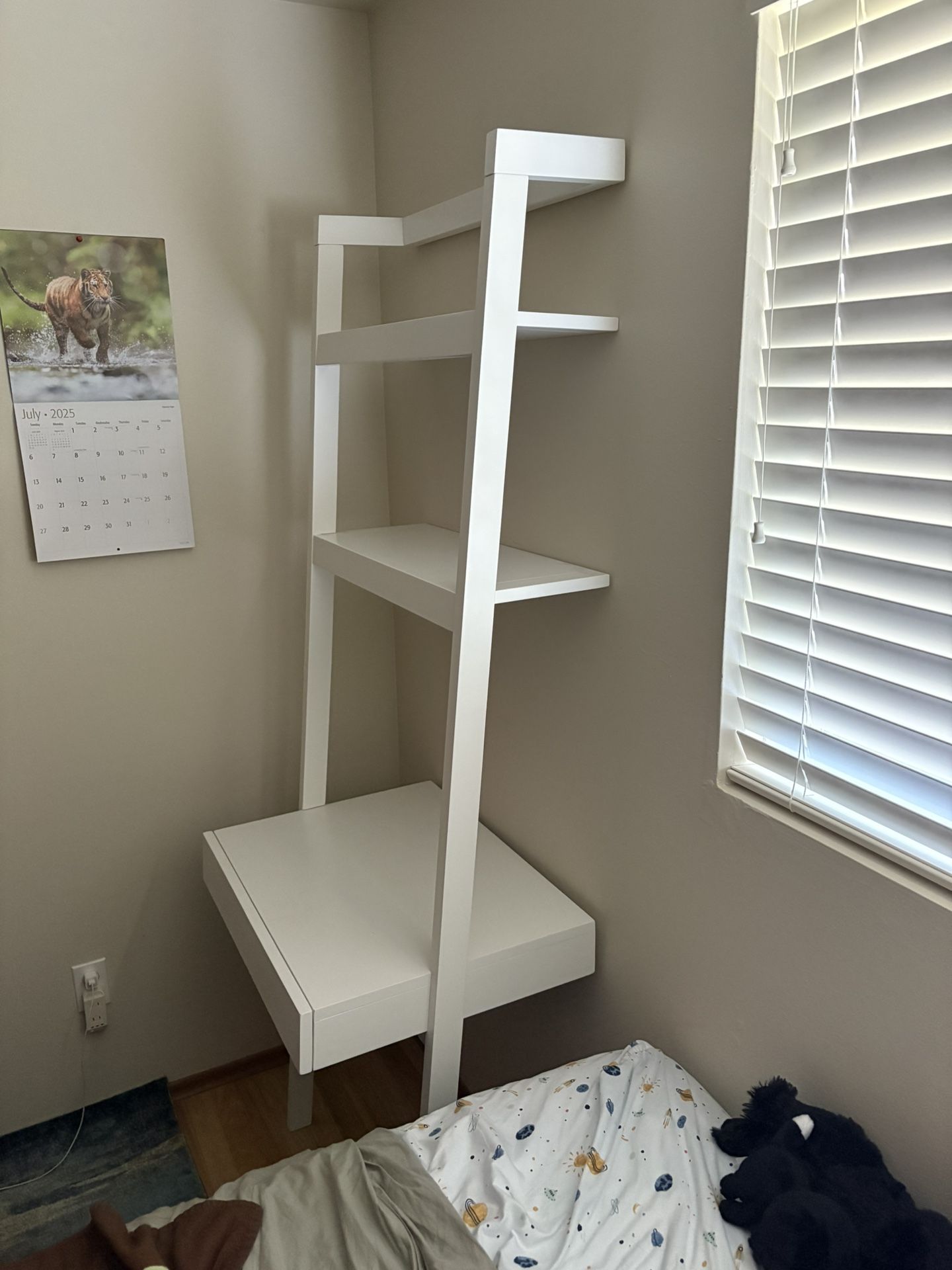 Crate and barrel desk that leans up against the wall with shelves