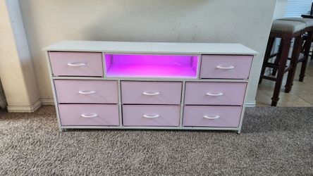 8 Drawer White & Pink Metal and Wooden Dresser/Up to 65" TV Stand with Shelf, LED Lights and Charging Station. 58"W x 14"D x 26.5"H.
This is a cute