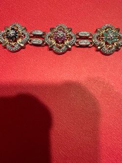 Silver bracelet with gold plated genuine stones has rubies sapphires and emeralds. I lowered the price to $100.