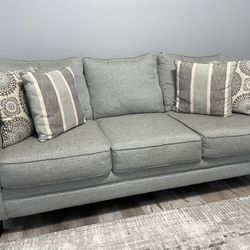 3 light grey couches with pillows 