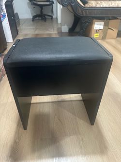 black vanity stool with a cushioned faux leather seat, commonly included with makeup dressing tables or desks. 16 by 16 inches