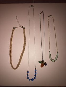 Bundle of 4 different style and length necklaces. One blue ad a bead necklace, a beige and silver choker, a cream stone on gold necklace, and one wit