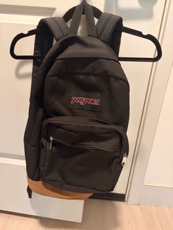 Jansport backpack with a black body & brown faux-leather bottom
