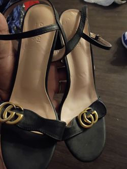 Gucci Marmont black leather sandals featuring the signature interlocking GG gold-tone logo on the front strap.