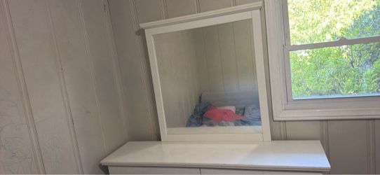 A white dresser with a mirror