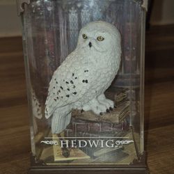 Display of Hedwig perched on a stack of books next to the Marauder's Map and Harry Potter's Wand