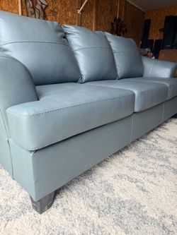 Ashley Genoa Steel sofa features a gray leather match finish and flared arms.