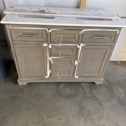 Thompson 48 in. W x 22 in. D Bath Vanity in Silver Gray with Engineered Stone Vanity in Carrara White with White Sink. Está pokito maltratado no afect