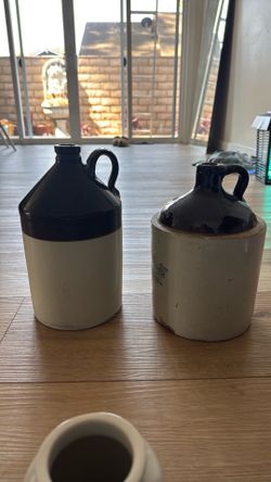Vintage “moonshine" or whiskey crocks, featuring a dark brown glazed top