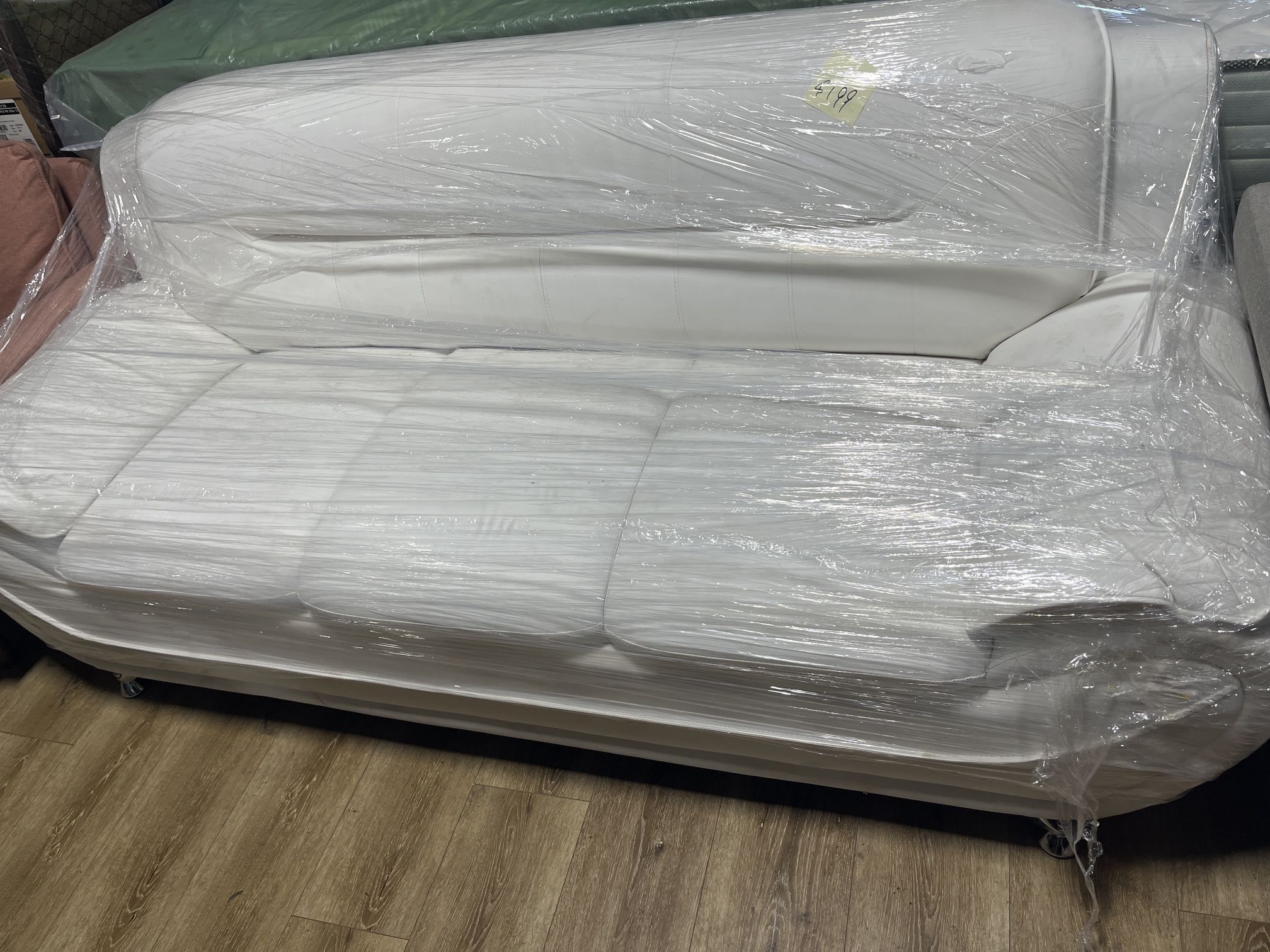 Brand new white sofa wrapped in plastic.