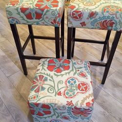 Two white-red-yellow floral padded stools and ottoman