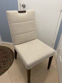 4 Beautiful Beige Fabric Dining Chairs with Walnut Wood Legs and a Small Detail on the Backrest; BRAND NEW.