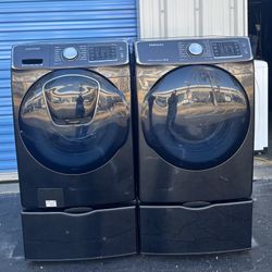 Samsung front-loading washer and dryer set in black stainless steel with pedestals