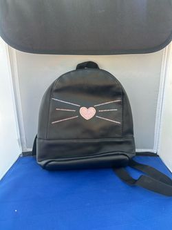 black faux-leather mini backpack featuring stitched whiskers and a sparkly pink heart detail.