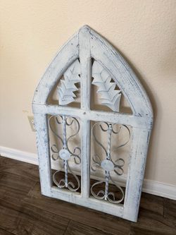 rustic, whitewashed arched wooden window frame featuring decorative metal scrollwork