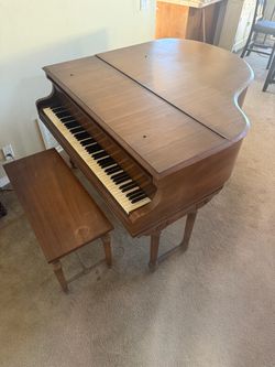 Vose & Sons of Boston baby grand piano, with a matching wooden bench and a traditional brown wood finish.