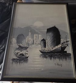 Framed black and white oil painting depicting traditional Chinese junk boats in a harbor, likely of Victoria Harbour in Hong Kong.