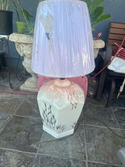 Vintage ceramic table lamp has a cream-colored base with a brown wheat stalk pattern. The lamp includes a pleated fabric shade with a protective plast