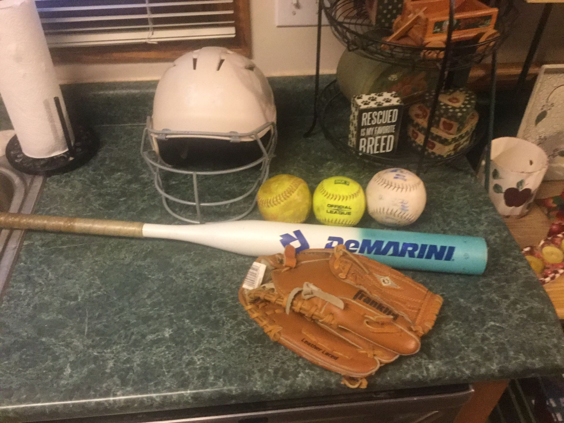 Softball package including a like new Franklin 11” glove, DeMarini softball bat 32” 21 ounce, Under Armour batting helmet with front cage and 3 so