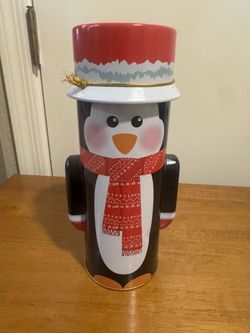 Penguin Christmas tin with white penguin wearing a red scarf with white snowflake pattern and a red hat with white trim #christmas #holiday It’s 9.5 i