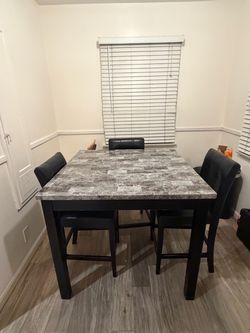 Counter height dining table with three leather chairs