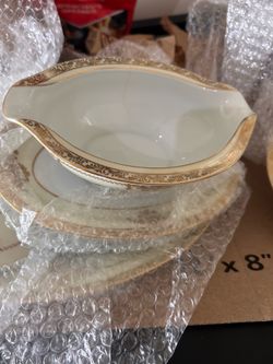 Noritake "Bancroft" creamer featuring intricate gold encrusted floral and basket designs on a delicate cream-colored porcelain.