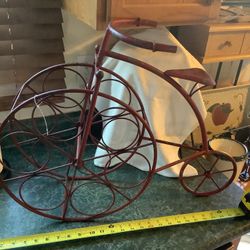 Charming Wrought Iron distressed red Wine rack in the shape of a 19th century tricycle Stands about 18” tall and 26” long about 12” deep Beautiful con