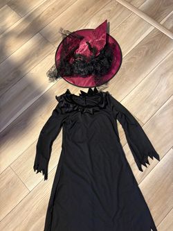 child's witch costume features a classic black dress with jagged sleeve cuffs with hat