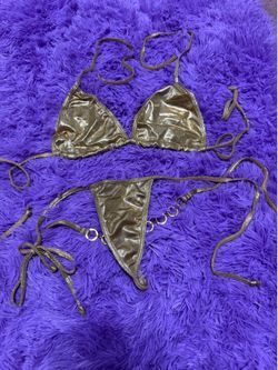 Shimmery metallic gold bikini with adjustable string ties. Triangle top with halter and back ties. Low-rise bottom with ring detail at hips. Statement