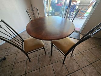 Round wooden table with four cushion chairs