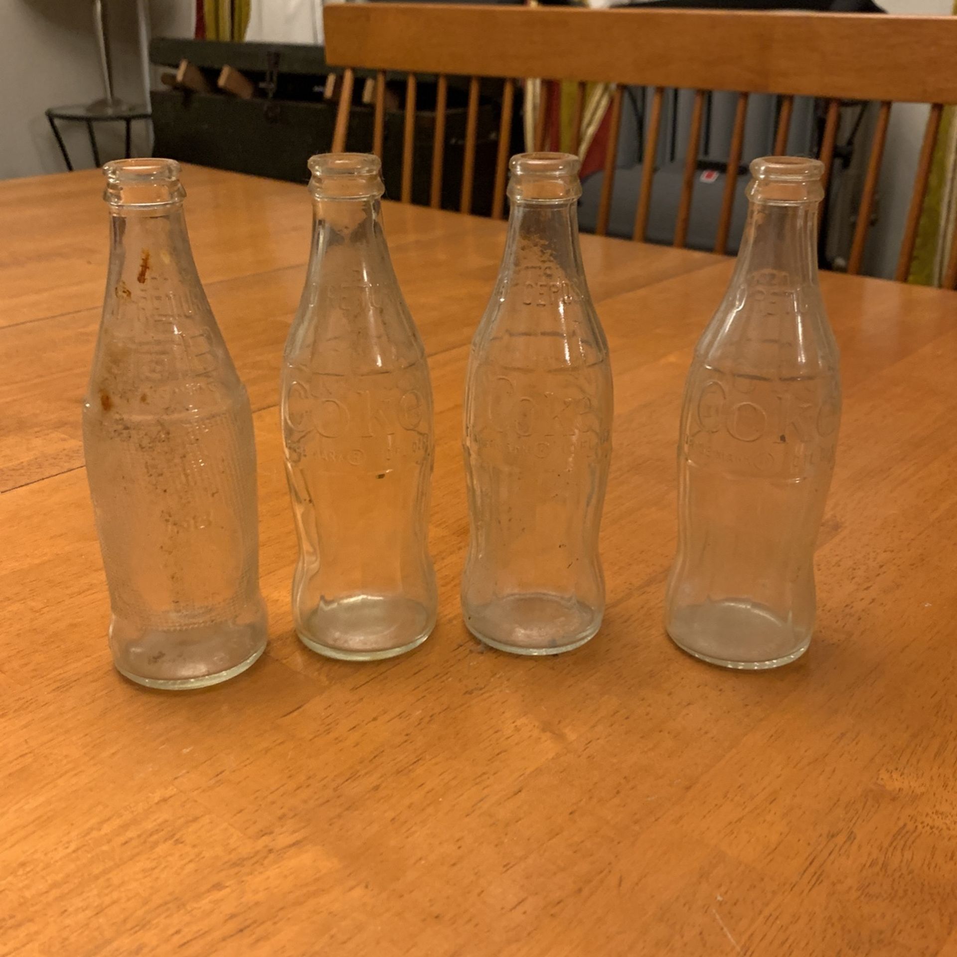 Four antique soda bottles, three Coca-Cola and one tab