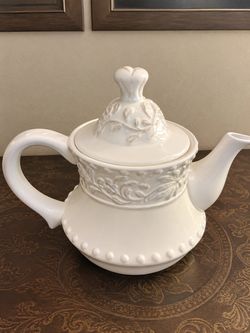 ivory or white ceramic teapot featuring an embossed floral and vine pattern
