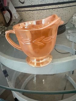 This is a vintage Fire-King Peach Lustre creamer jug from the 1950s or 1960s.