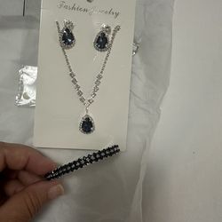 Cadena plateada con piedra azul oscuro, aretes y pulsera.