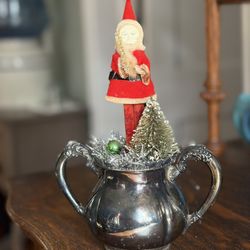 Antique/collectible Santa Claus standing on on a silver sugar bowl with Christmas tree