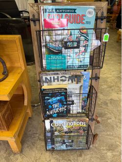 rustic-style magazine rack features a light wood frame with three black metal wire baskets suspended for storage.