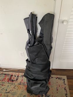 portable cot stored in a wheeled carrying bag.