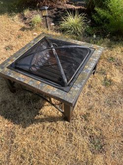 Sturdy square fire pit. Has tiled top edge and metal frame. Includes spark screen and cooking