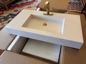 Solid surface sink basin with gold faucet.