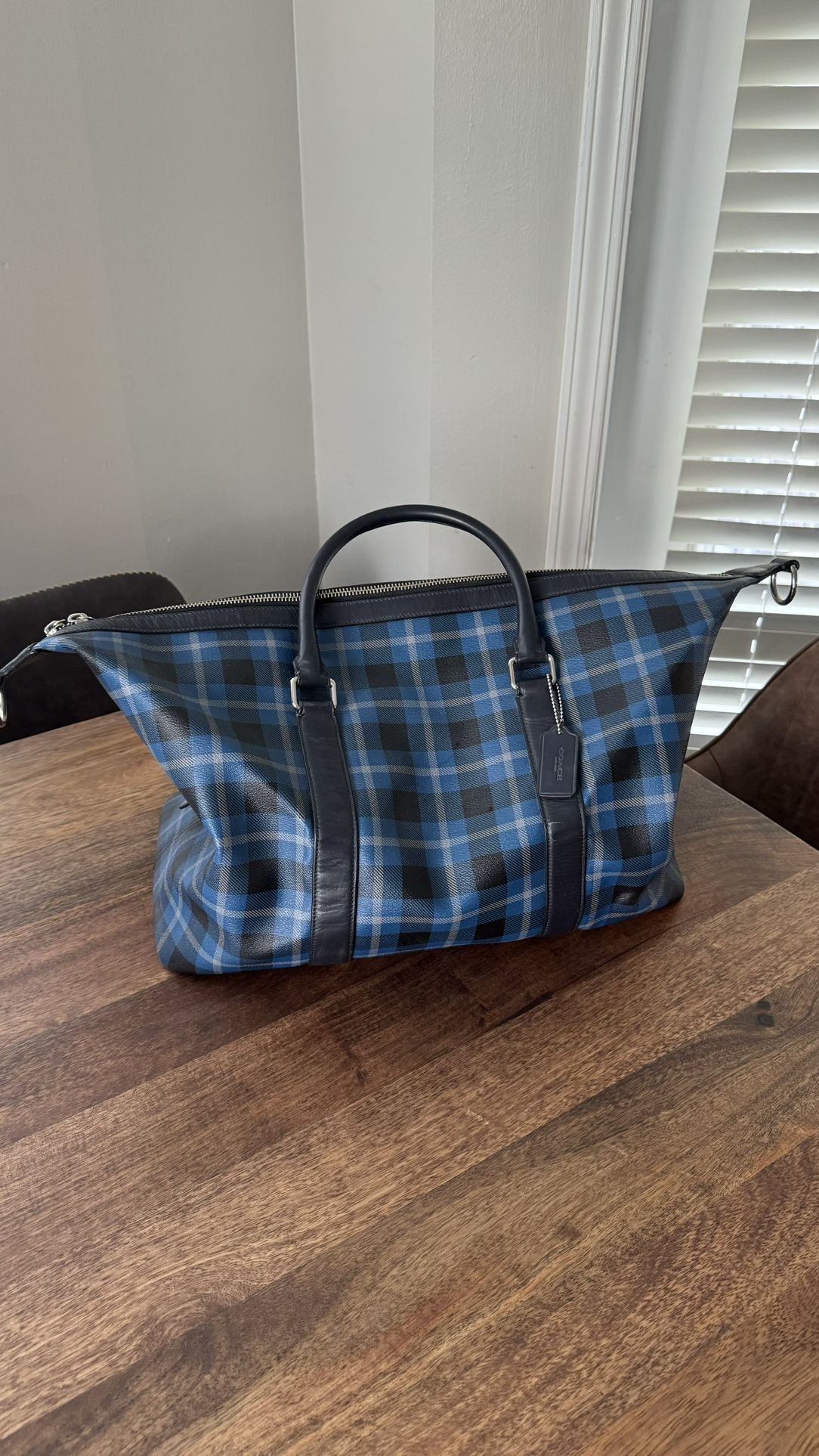 Coach Voyager Duffle Bag in a black and blue plaid pattern.
