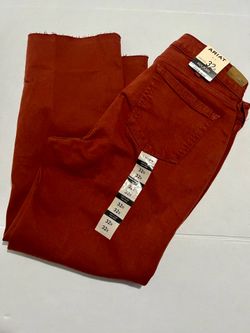 Ariat Kick Flare high-rise jeans in a rust red color, featuring a raw, frayed hem